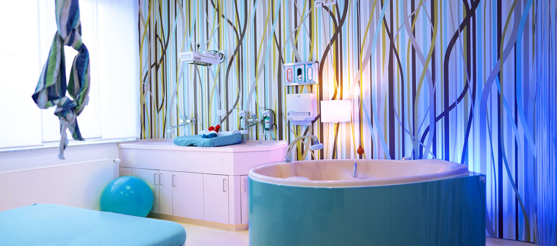 Heller, freundlich gestalteter Kreißsaal mit einer hellblauen Geburtswanne.