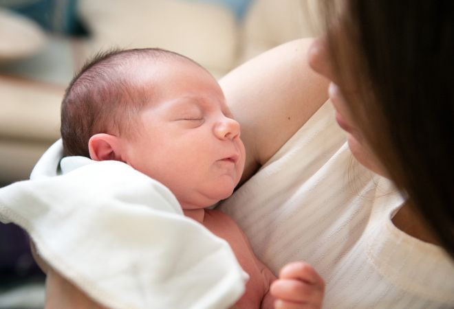 Ein Neugeborenes auf dem Arm der Mutter.