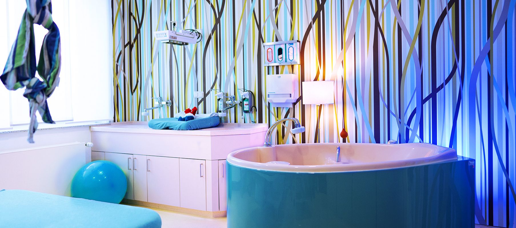 Heller, freundlich gestalteter Kreißsaal mit einer hellblauen Geburtswanne.